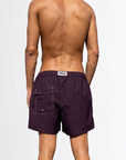 Person wearing purple swim shorts on a white background