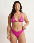 Woman wearing a sustainable moderate coverage pink bikini against a plain background