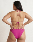 Woman wearing a pink bikini with a plain background