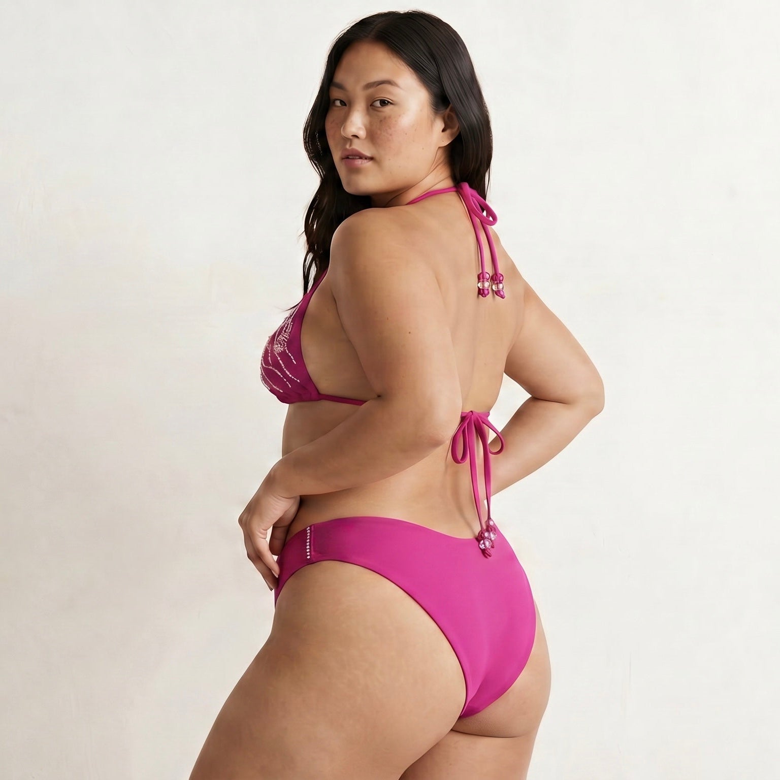 Woman wearing a pink sustainable bikini against a plain background