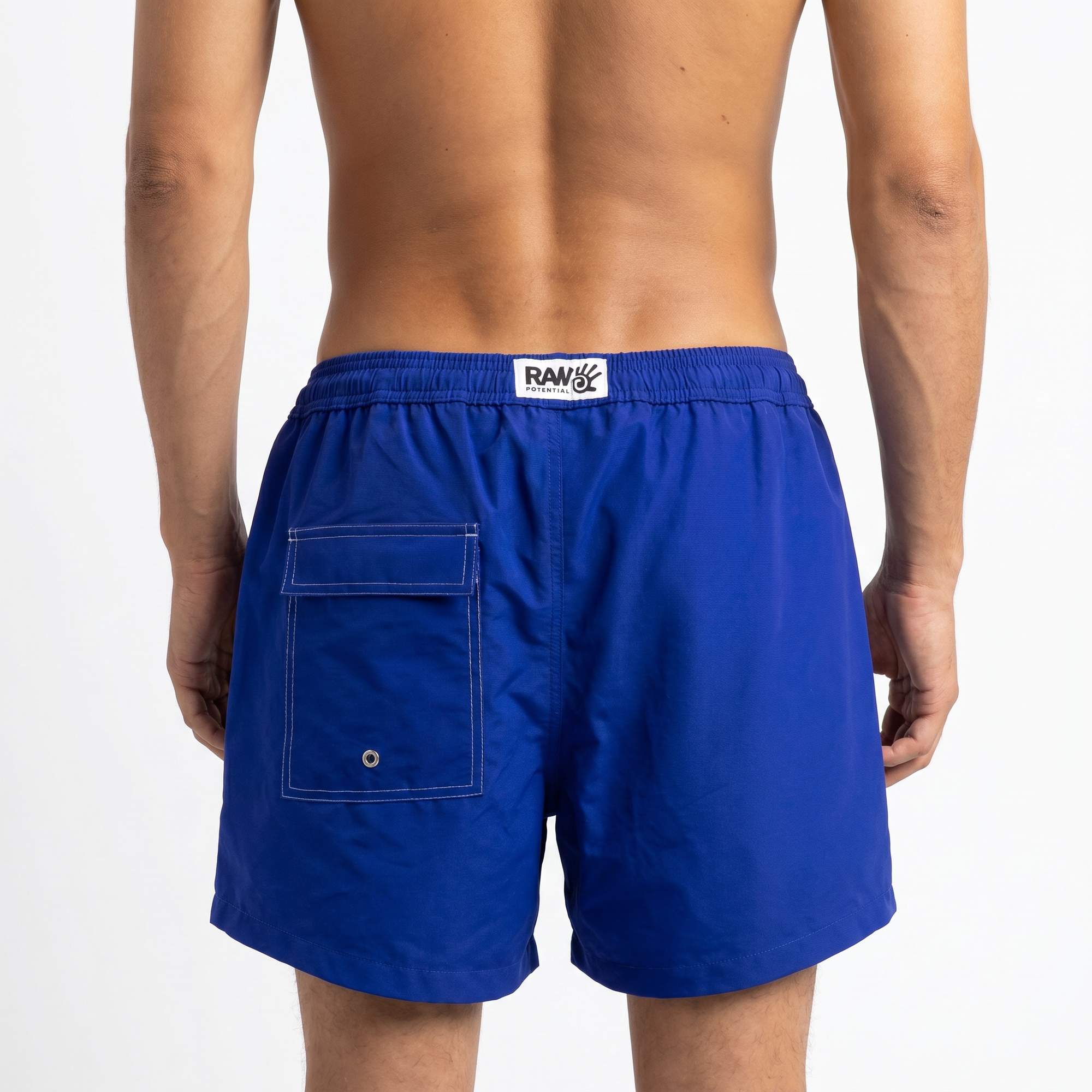 Blue swim shorts with a visible brand logo in the centre of the back of the waistband. A back pocket is visible, designed with subtle white stitching for a luxury feeling. The image is shot on a white background.