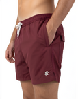 Burgundy mens swim shorts with a logo on a white background