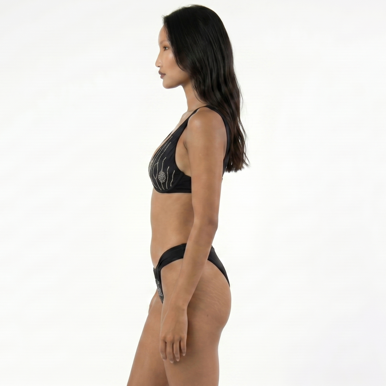Woman wearing a sustainable black bikini on a white background