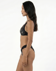Woman wearing a sustainable black bikini on a white background