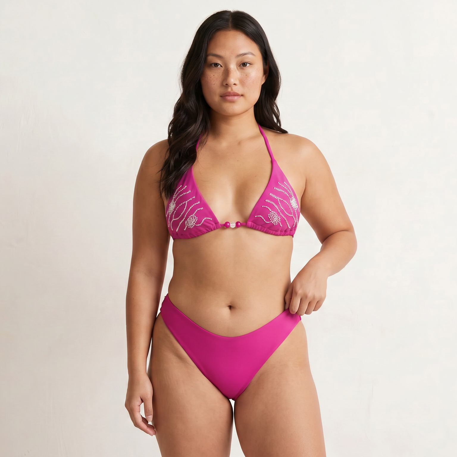 Woman wearing a sustainable moderate coverage pink bikini against a plain background
