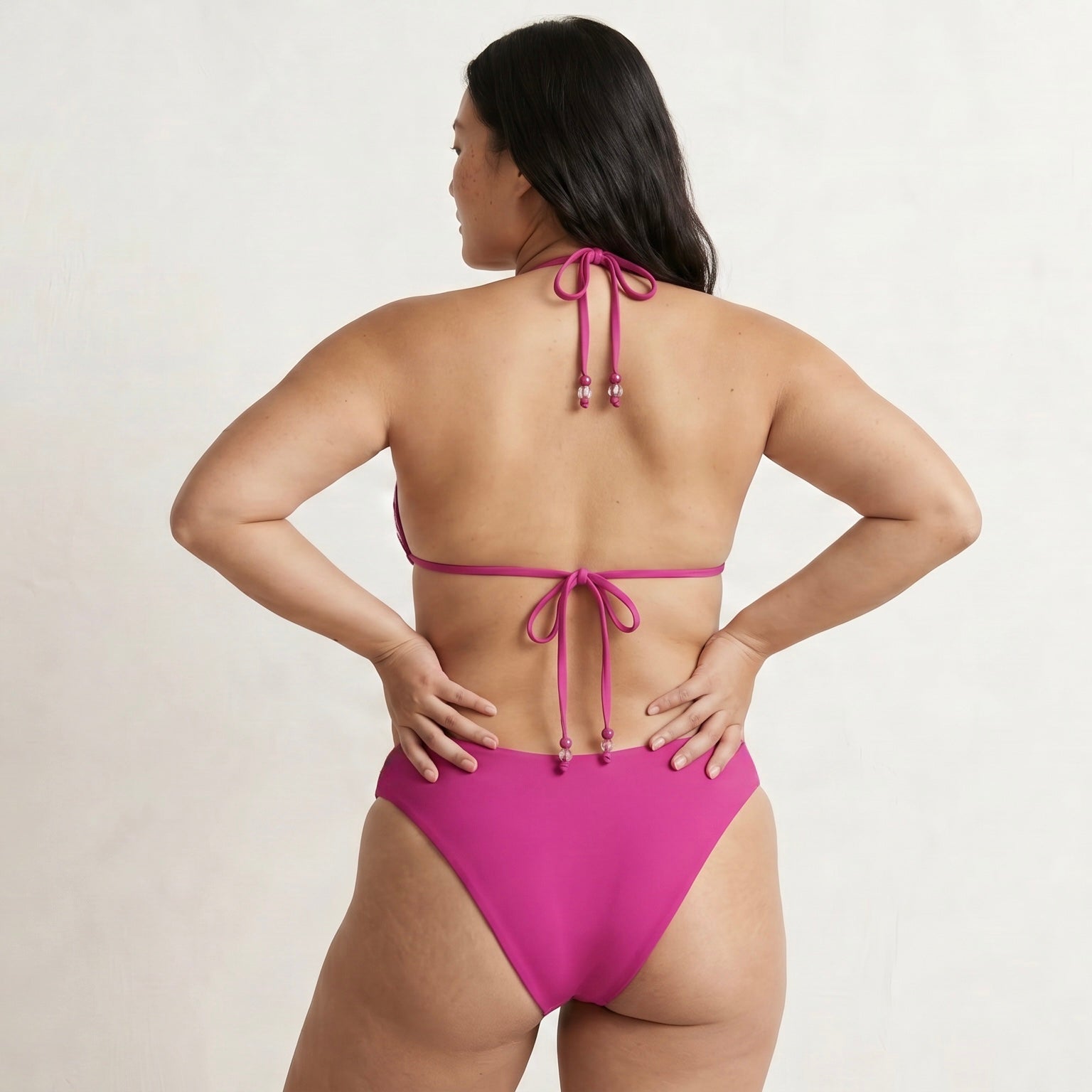 Woman wearing a pink bikini with a plain background